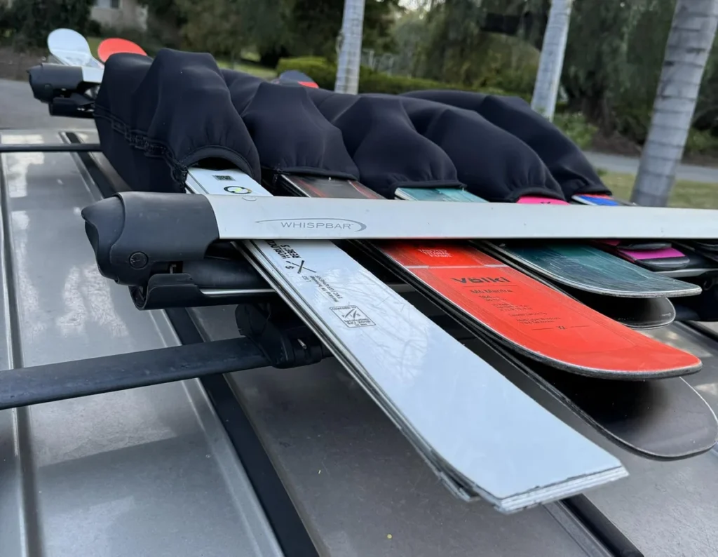 Neoprene ski binding travel sleeve protecting bindings on a ski rack during transport