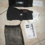 Dakine Wrist Guards (left and right) with straps, mesh storage bag, and manual laid out on tile floor.