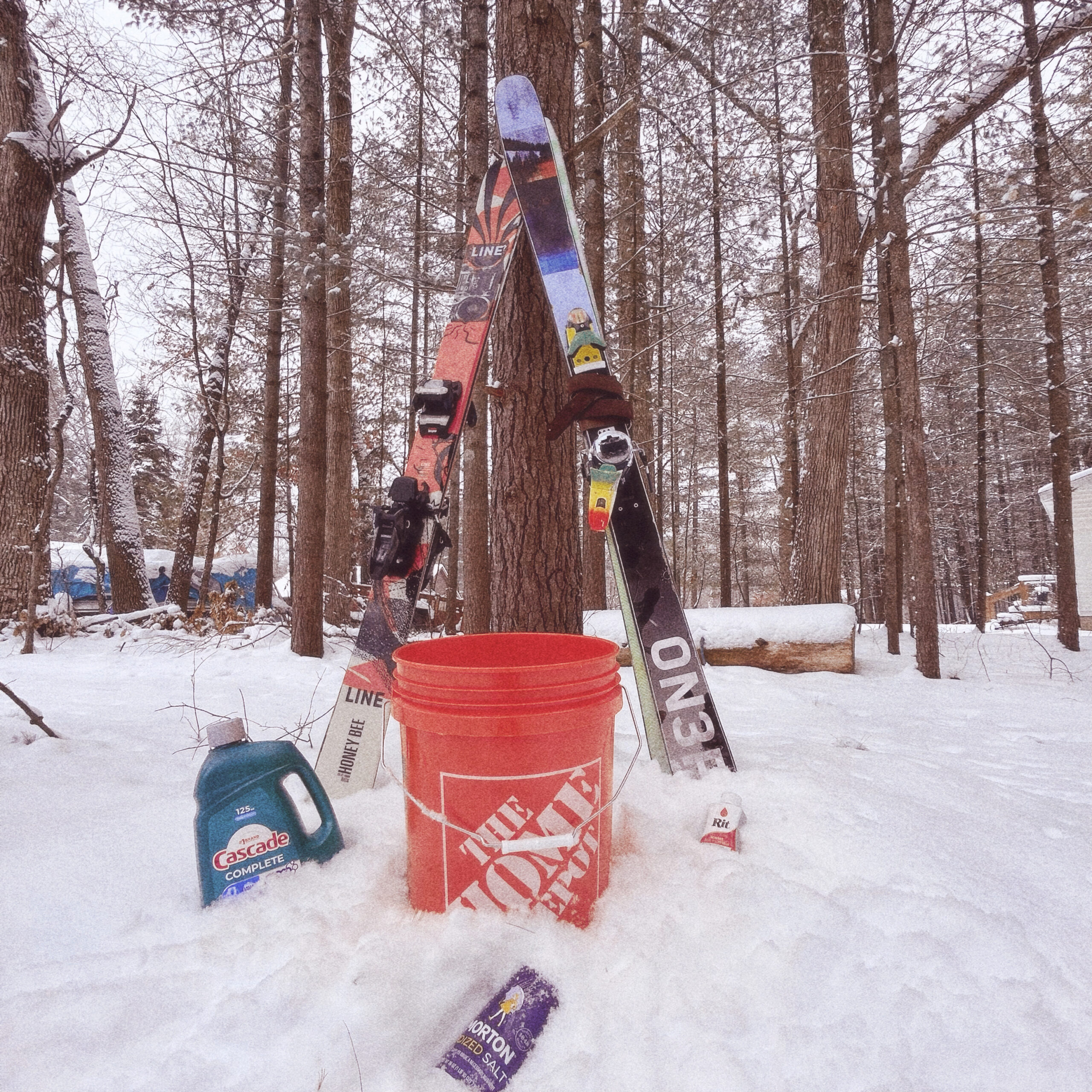 Dye setup outdoors with empty bucket, Cascade detergent, Morton salt, and Rit dye staged in snow