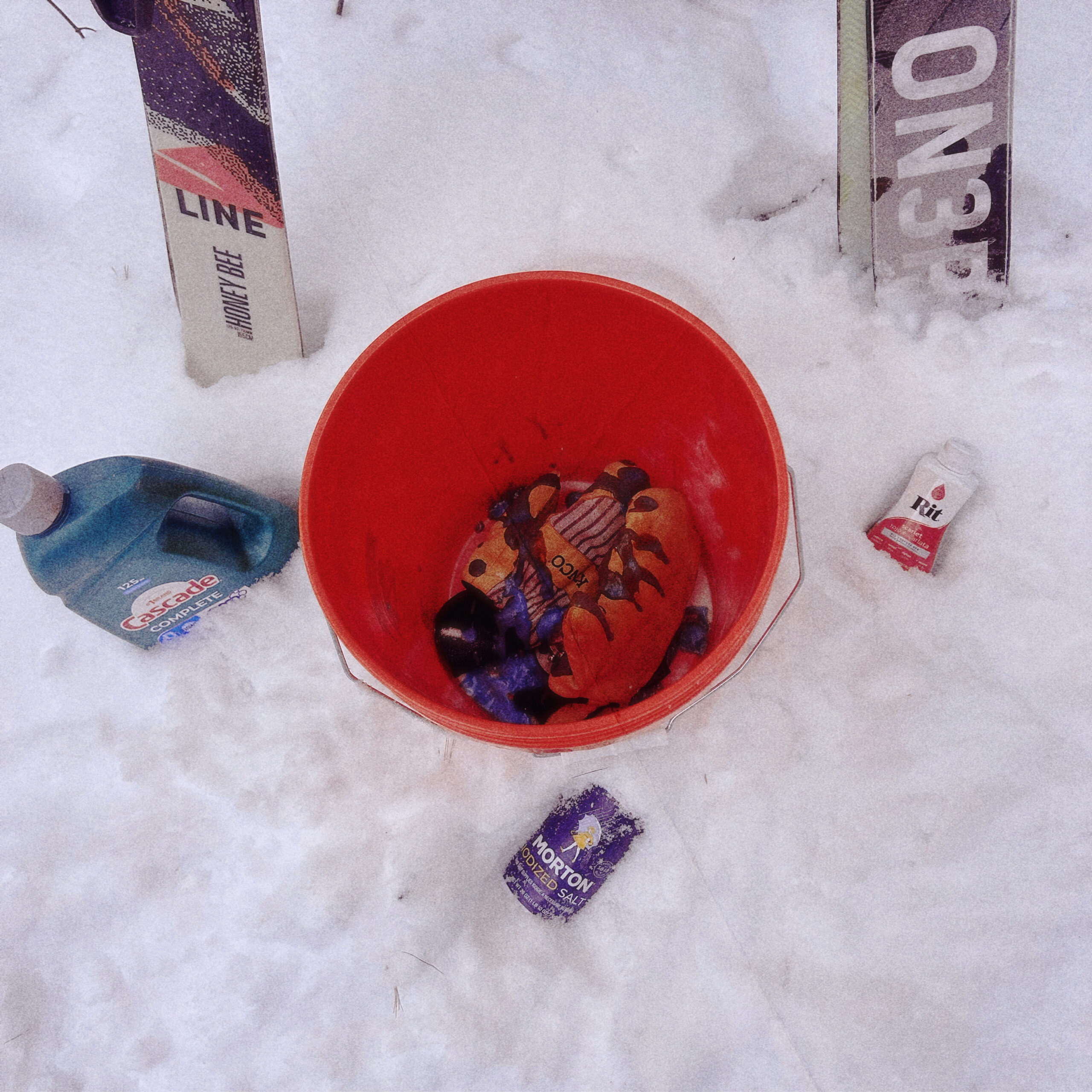 Kinco mittens soaking inside a red bucket dye bath